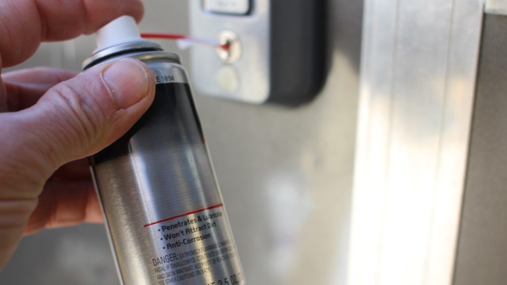 A homeowner using a spray lubricant to lubricate locks